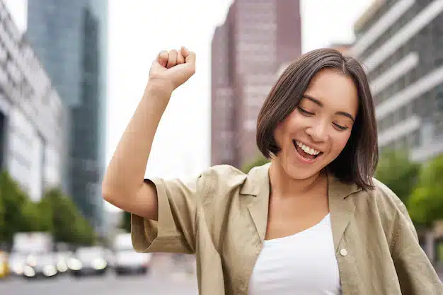 Happy people young smiling asian woman dancing city raising hands up city