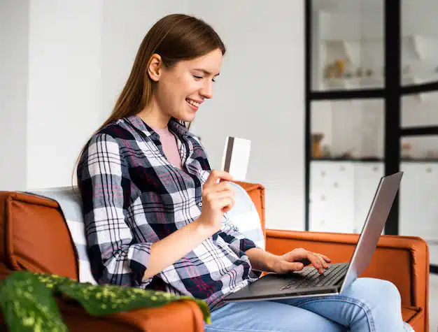 Sideways woman looking her laptop holding credit card 23