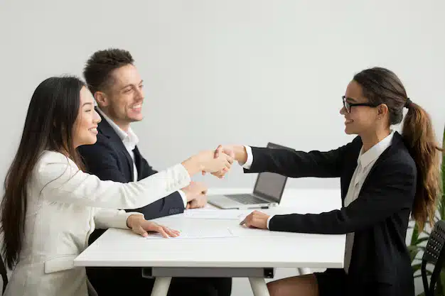 Smiling diverse businesswomen shake hands group meeting deal concept
