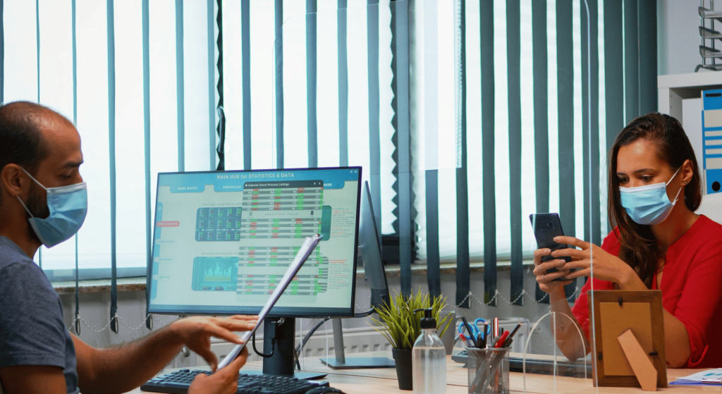 Pharmacy staff reviewing a data dashboard on a computer monitor