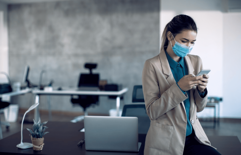 Healthcare professional wearing a mask while checking her phone in an office